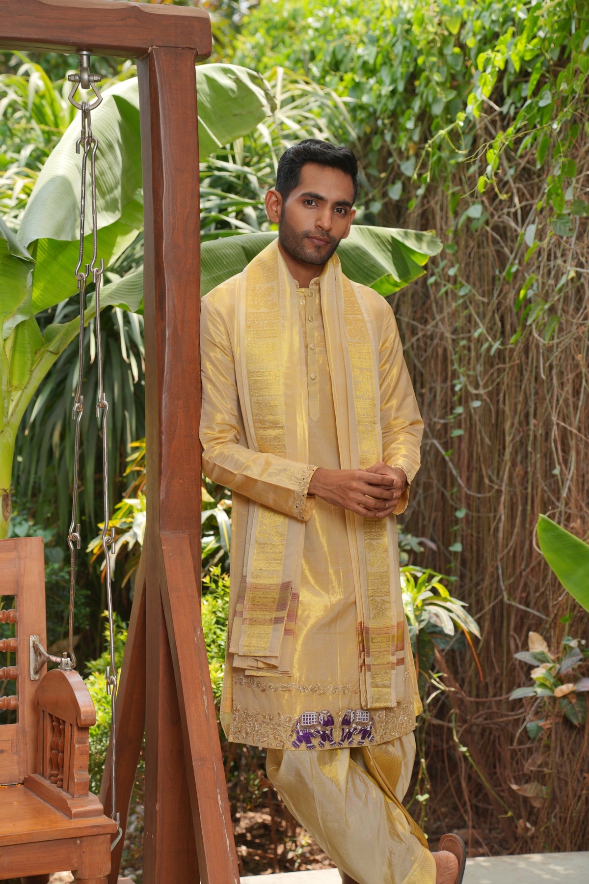 Man in a gold tissue pattu kurta set in a garden